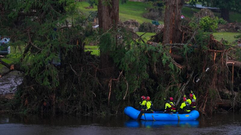 ARCHIVO - Se ve a los equipos de rescate en una embarcación mientras buscan a personas...