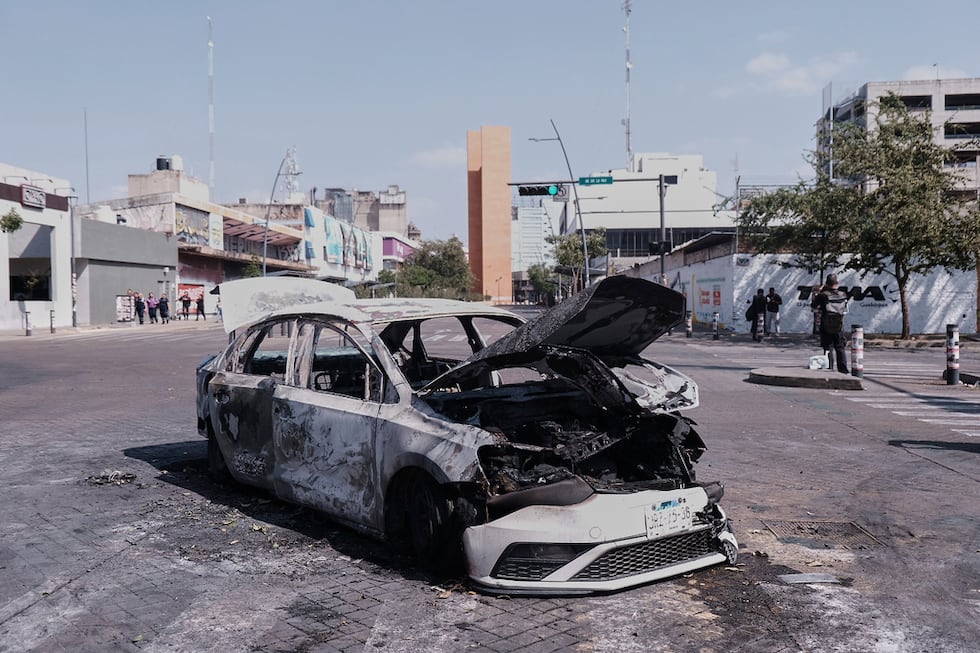 Un vehículo yace carbonizado tras ser incendiado en una avenida de Guadalajara, en el estado...