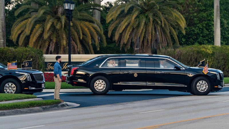 El presidente Donald Trump saluda desde su limusina al salir del Trump International Golf...