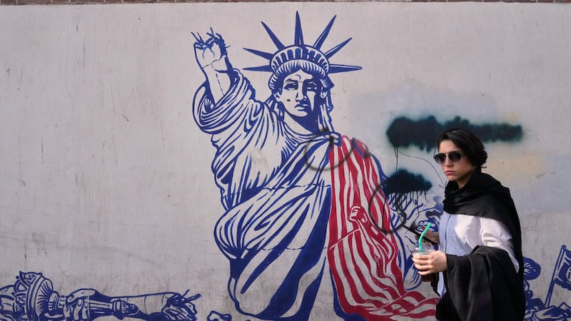 Una mujer pasa junto a un mural antiestadounidense en la pared de la antigua embajada de...