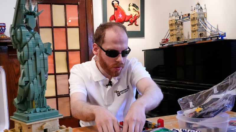 Matthew Shifrin, fundador de Bricks for the Blind, palpa piezas específicas mientras construye...