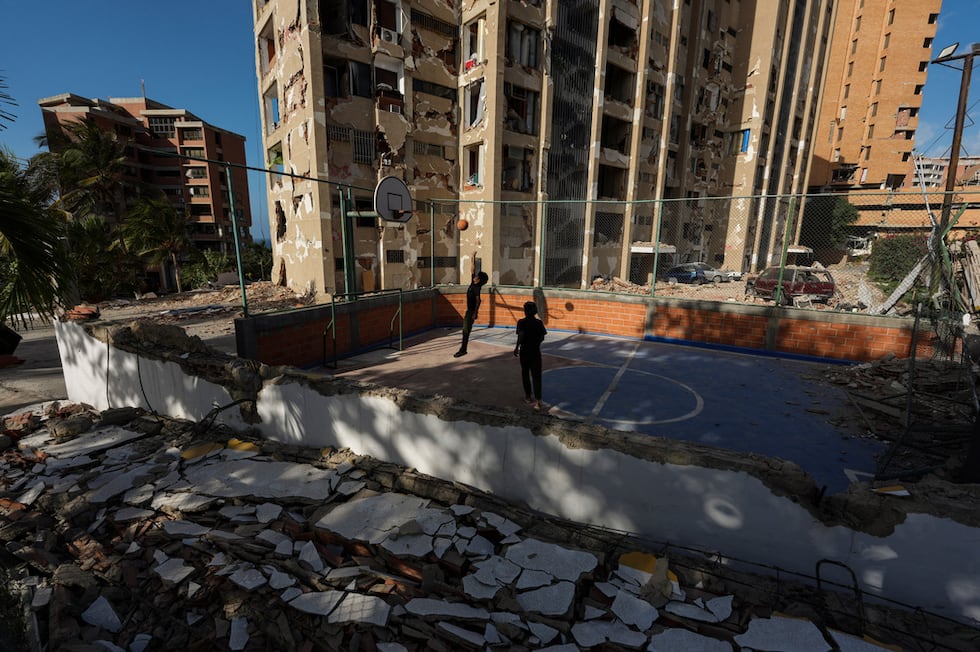 Niños juegan al baloncesto cerca de edificios destruidos por los terremotos que azotaron Catia...