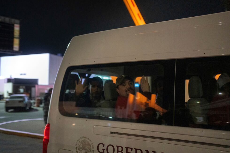 Migrantes que fueron deportados de Estados Unidos a México saludan mientras son transportados...